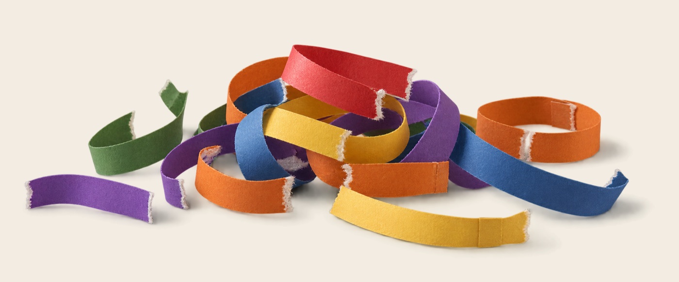 A pile of torn paper-chain links in red, orange, yellow, green, blue, and purple